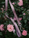 Pink GENTLEBEAST dog leash displayed on a wooden surface with a soft focus background.