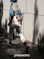 Person walking with a 'paaaata' bag against a textured wall