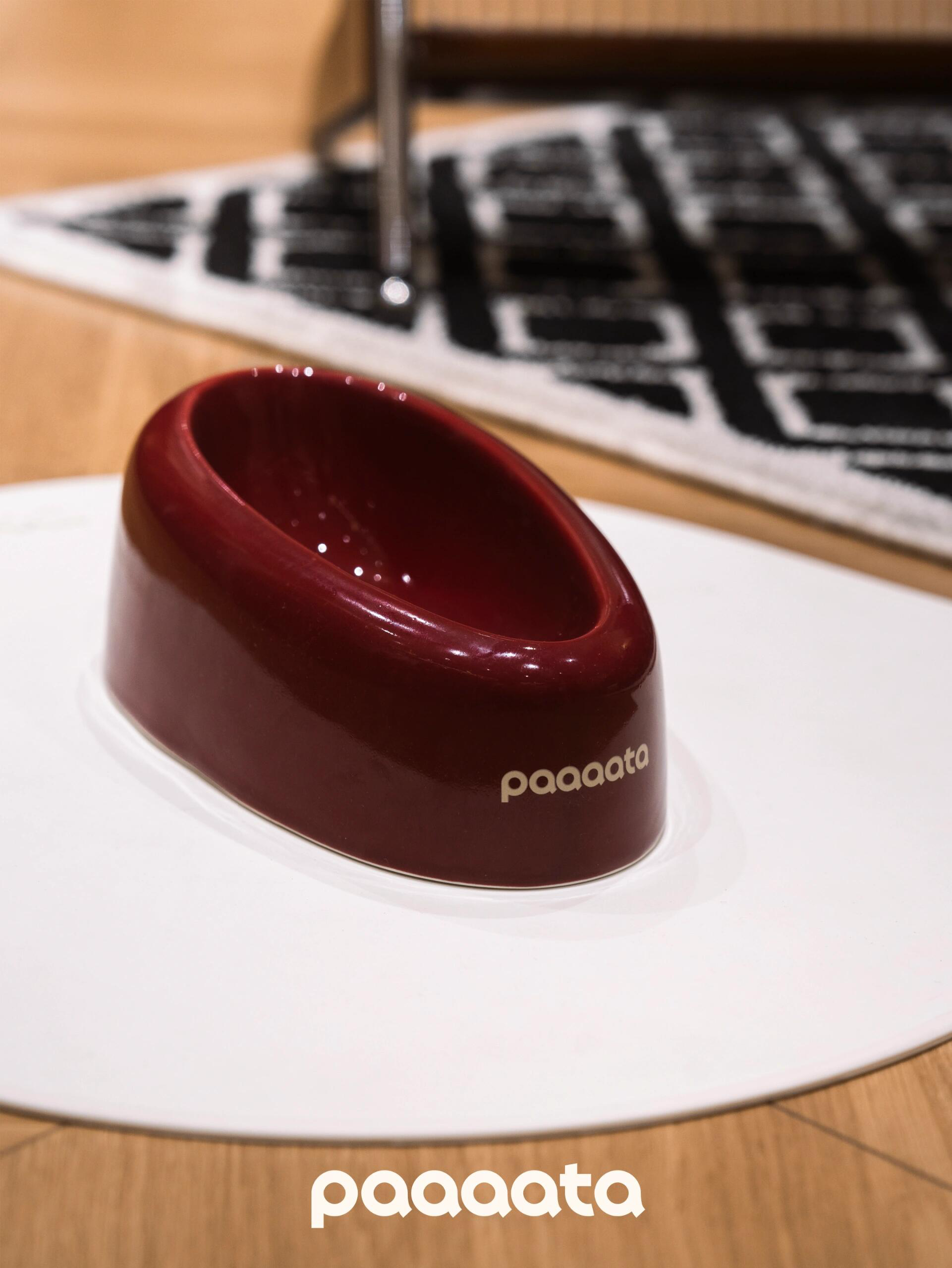Red pet bowl with 'paaaata' branding on a white surface.