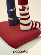 Two pairs of socks with animal patterns on a red cushion, featuring the brand 'paaaata'.