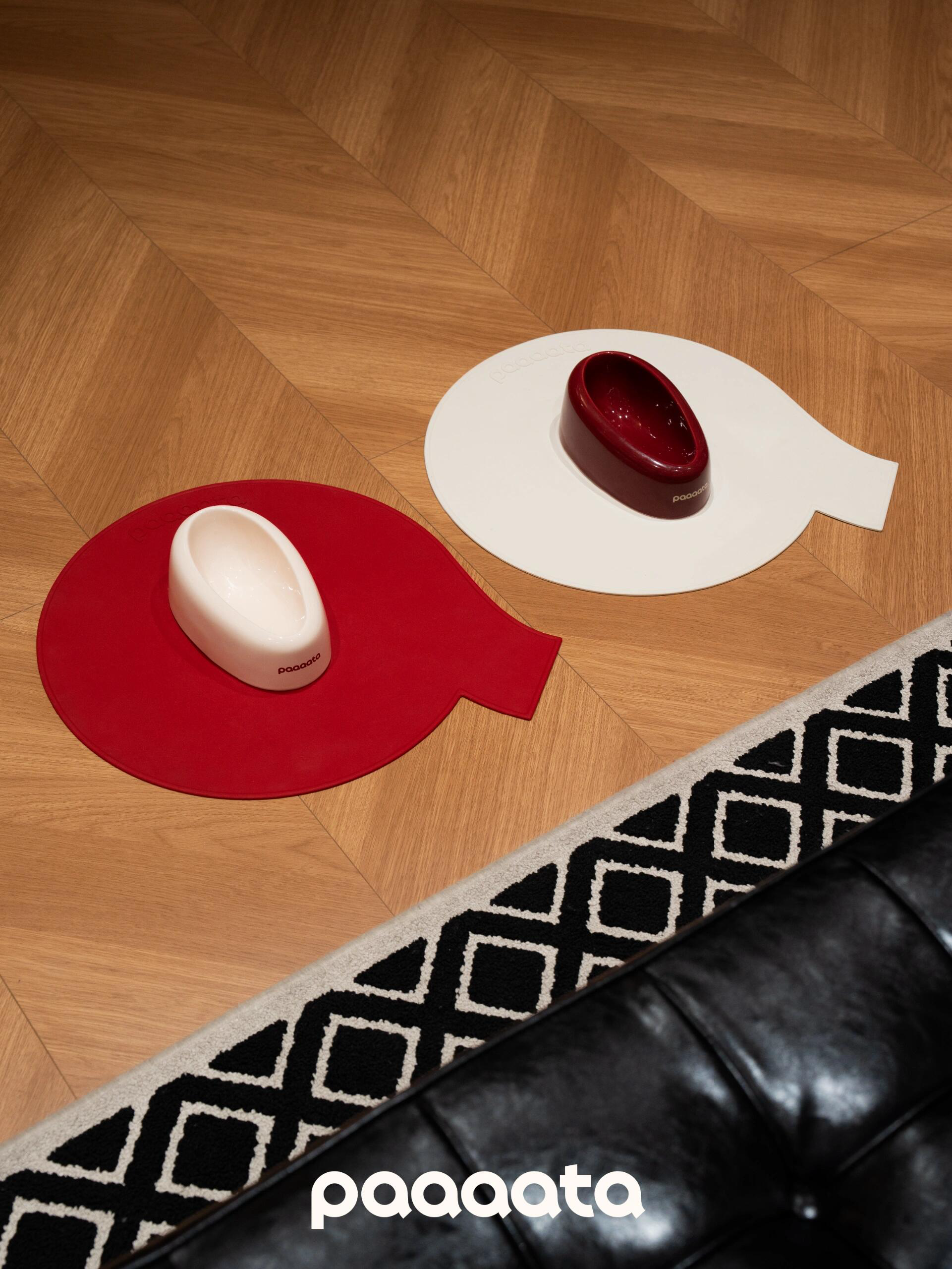 Two red and white coasters on a wooden floor with 'paaaata' branding.