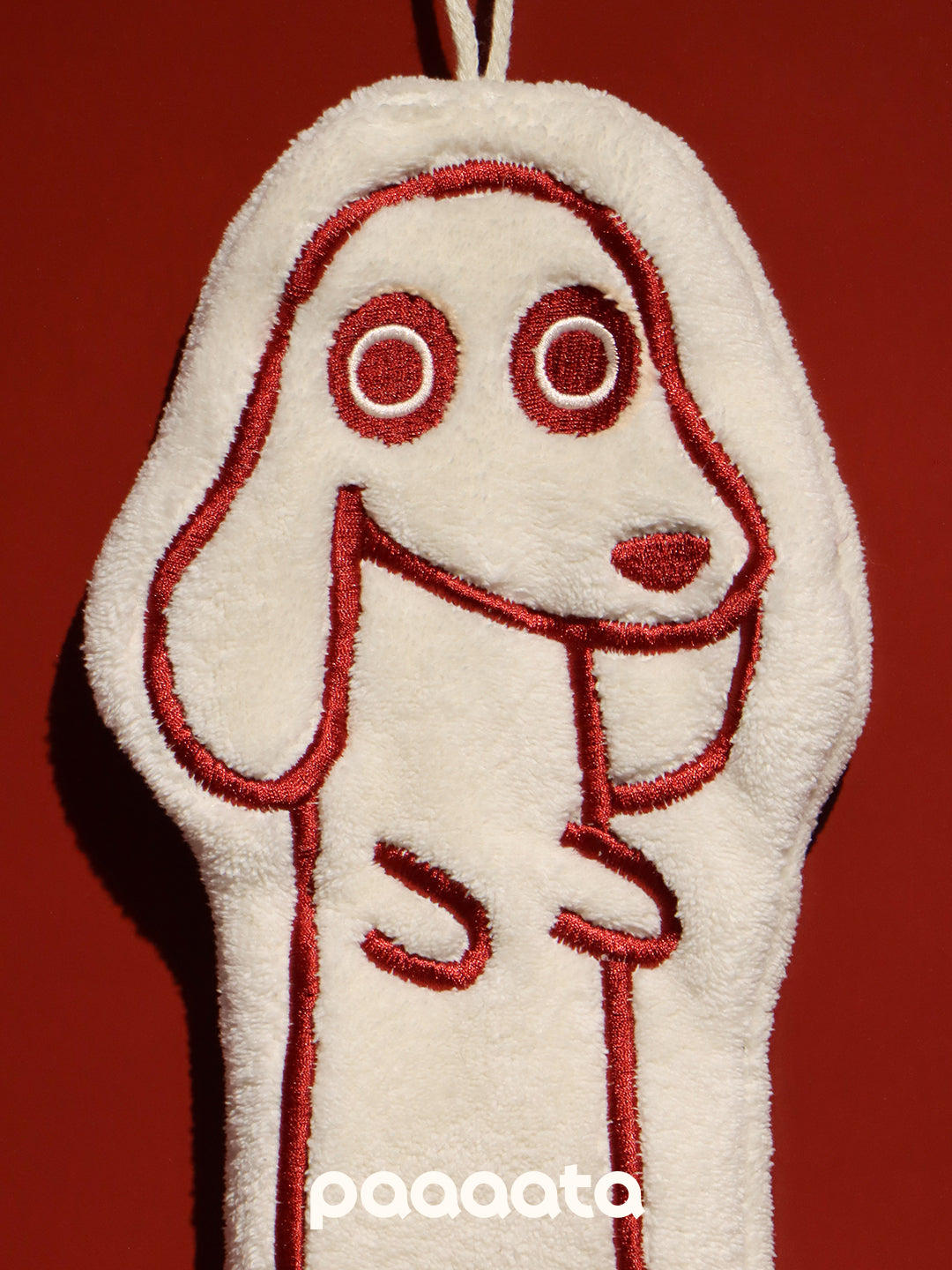 White paaaata hand towel with red embroidered face on a red background, featuring the brand 'paaaata'.