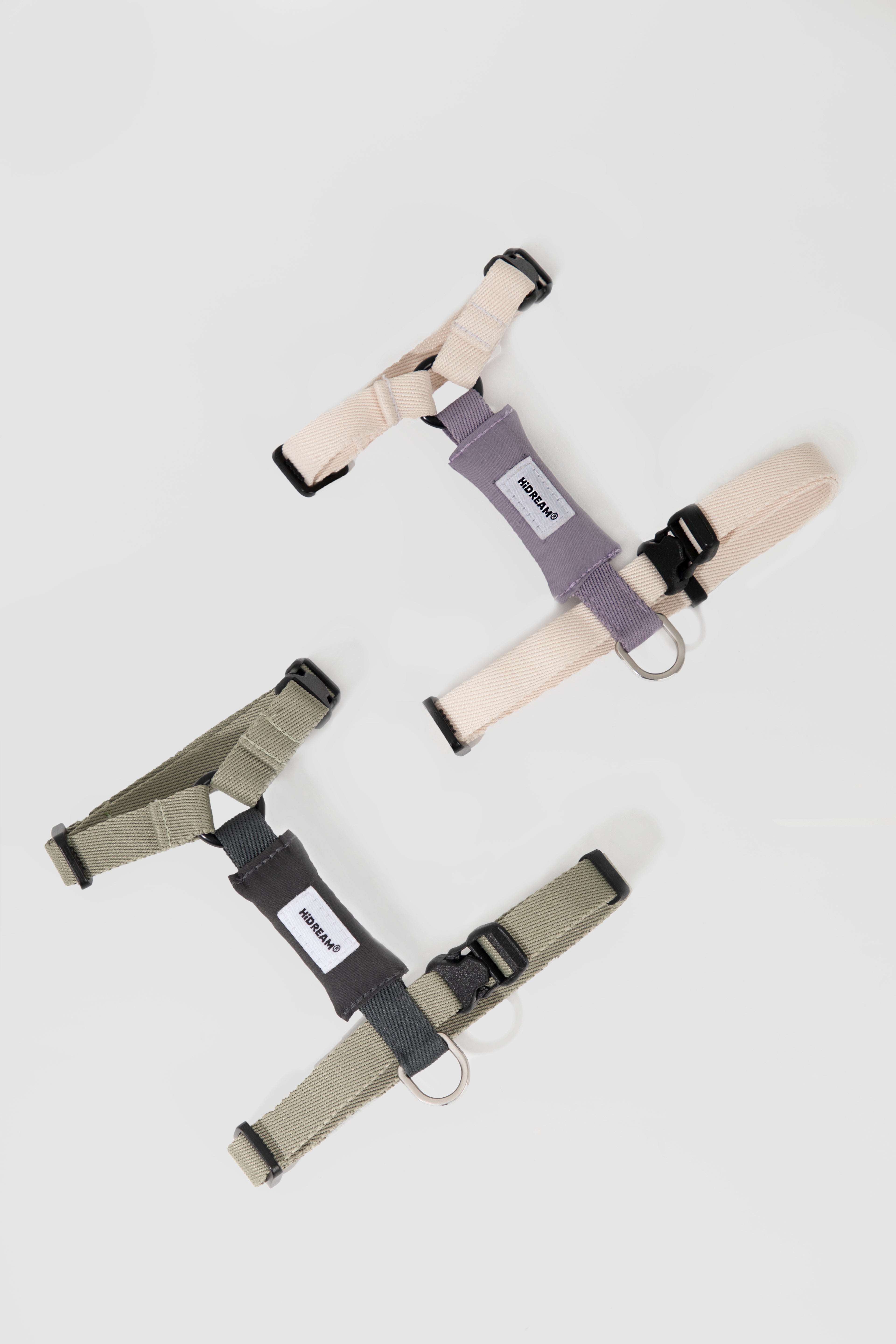 Flat lay of two lightweight adjustable cat harnesses in different colors, showing the I-shaped design, D-ring attachment, and strap adjusters.
