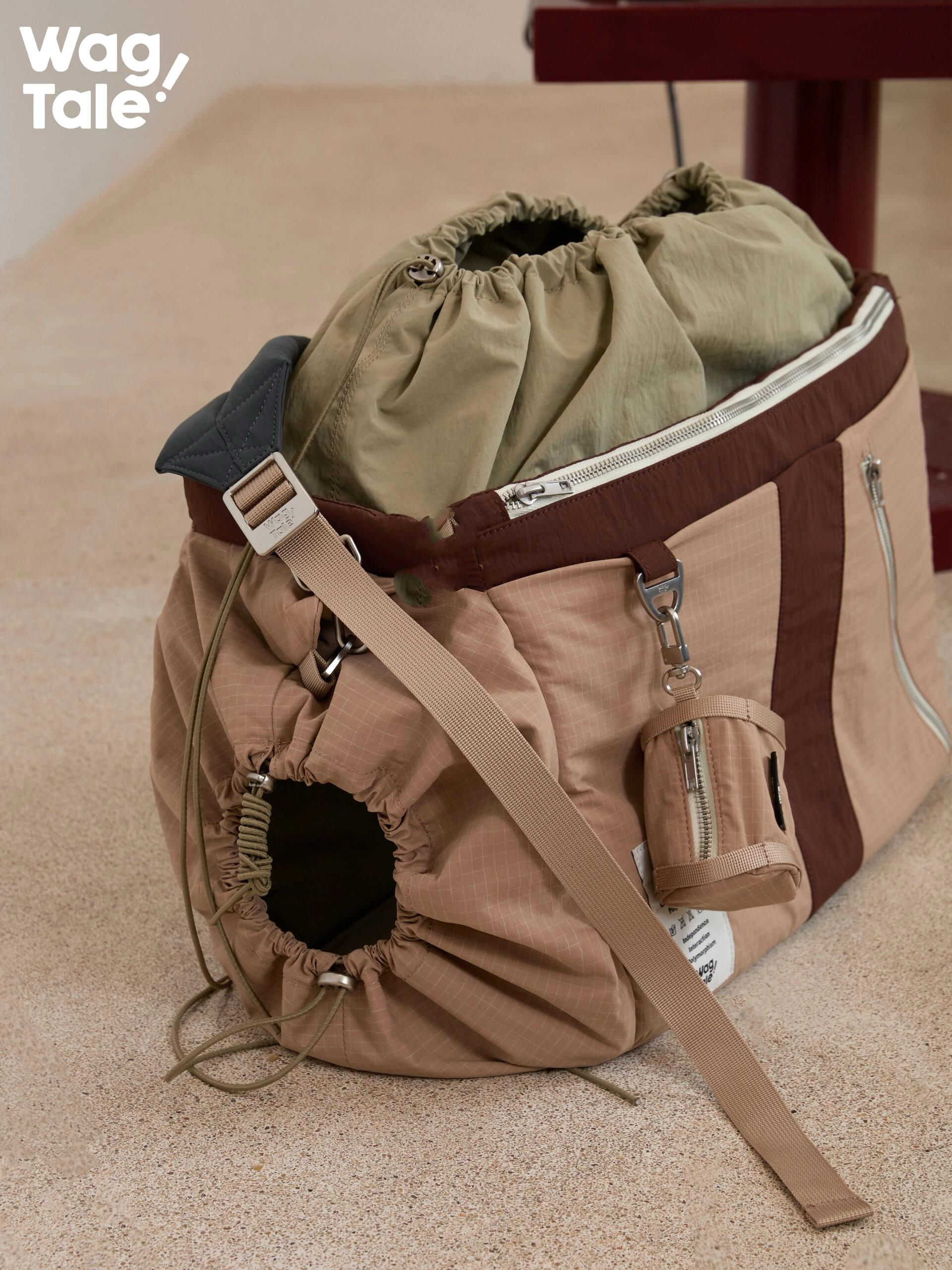 Adjustable dog carrier bag showing side drawstring opening, padded shoulder strap, elastic entry design, and side storage pocket for small dog travel.