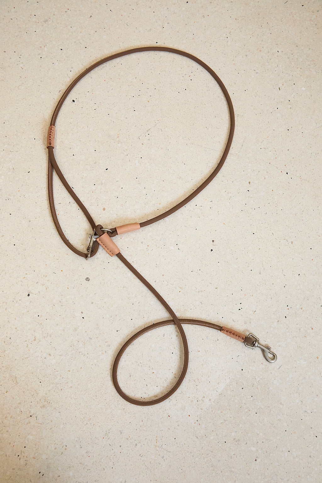 Flat lay of an adjustable waist dog leash in brown, highlighting the looped hands-free design, alloy hardware, and slim rope profile.