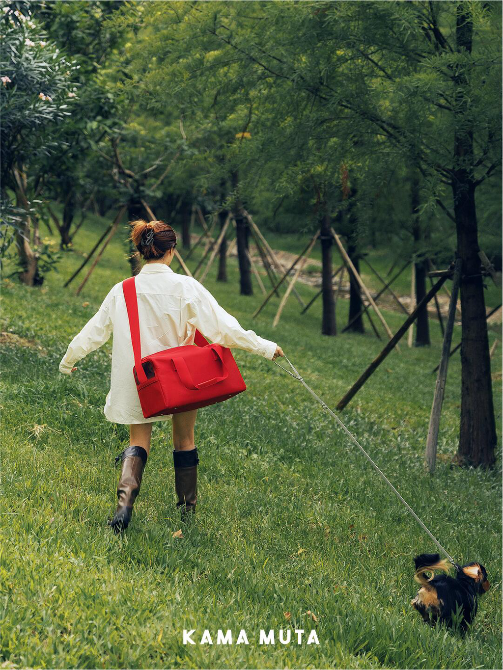 Person walking a dog outdoors with a red anti escape pet carrier bag worn across the body