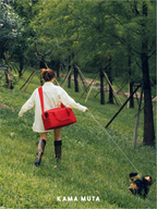 Person walking a dog outdoors with a red anti escape pet carrier bag worn across the body