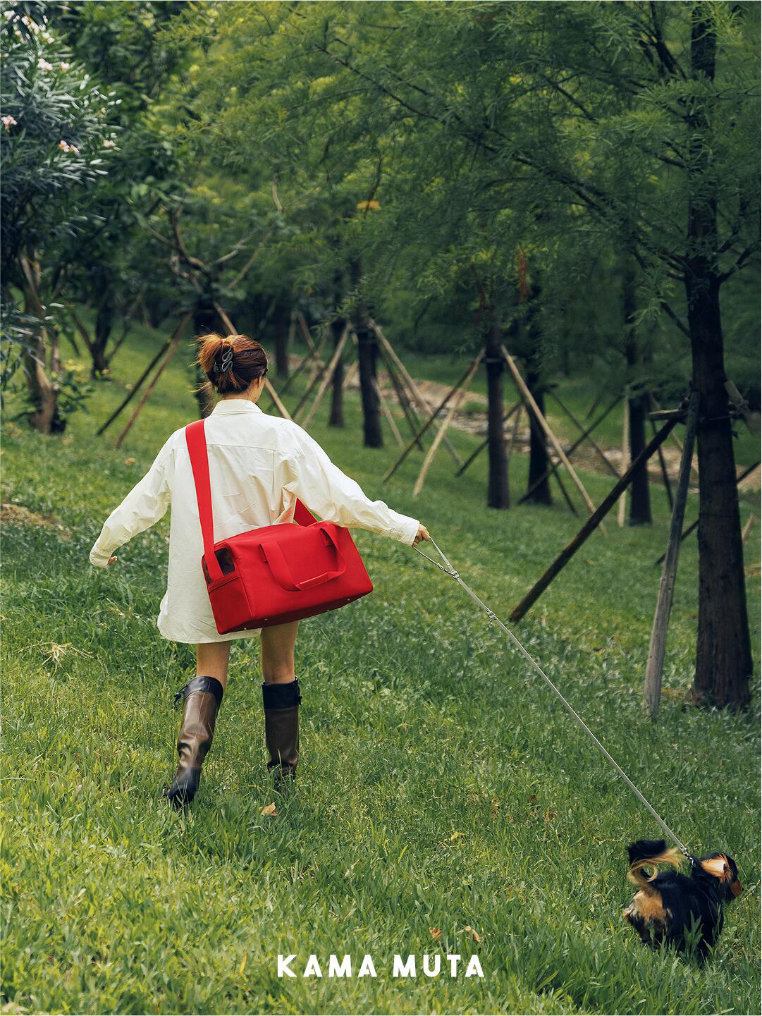 Person walking a dog outdoors with a red anti escape pet carrier bag worn across the body