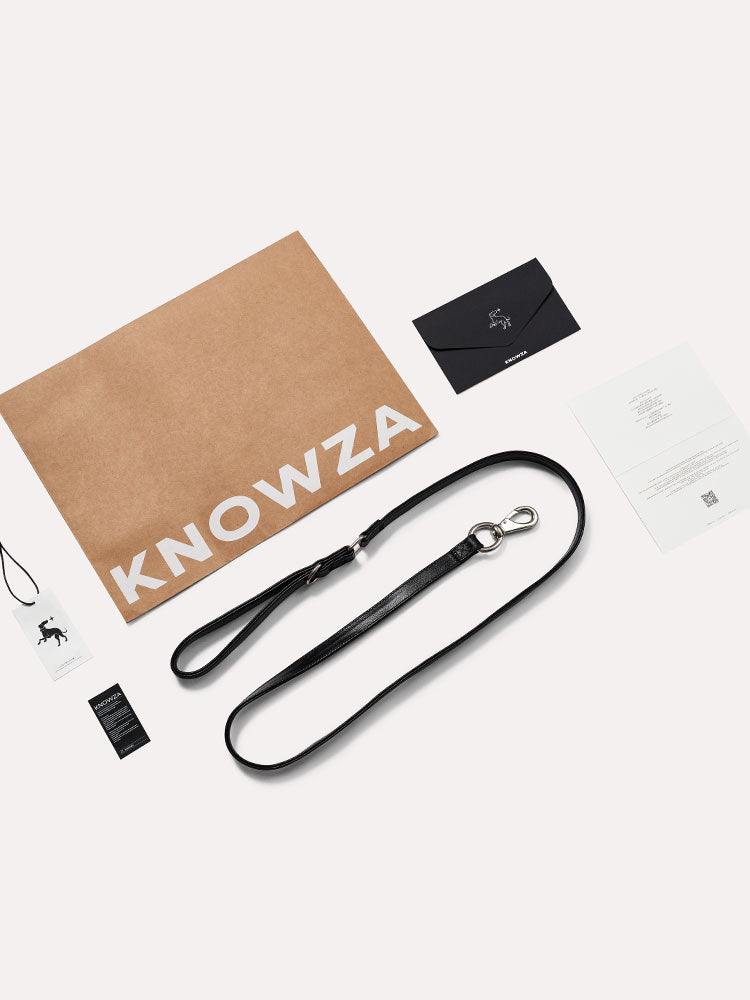 Black leather dog leash presented with branded packaging, tags, and accessories for a premium finish.