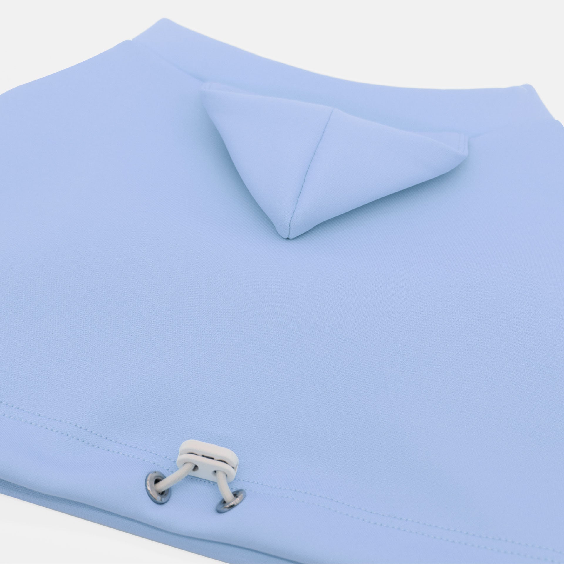 Light blue dog crop top with a white tag on a light gray background