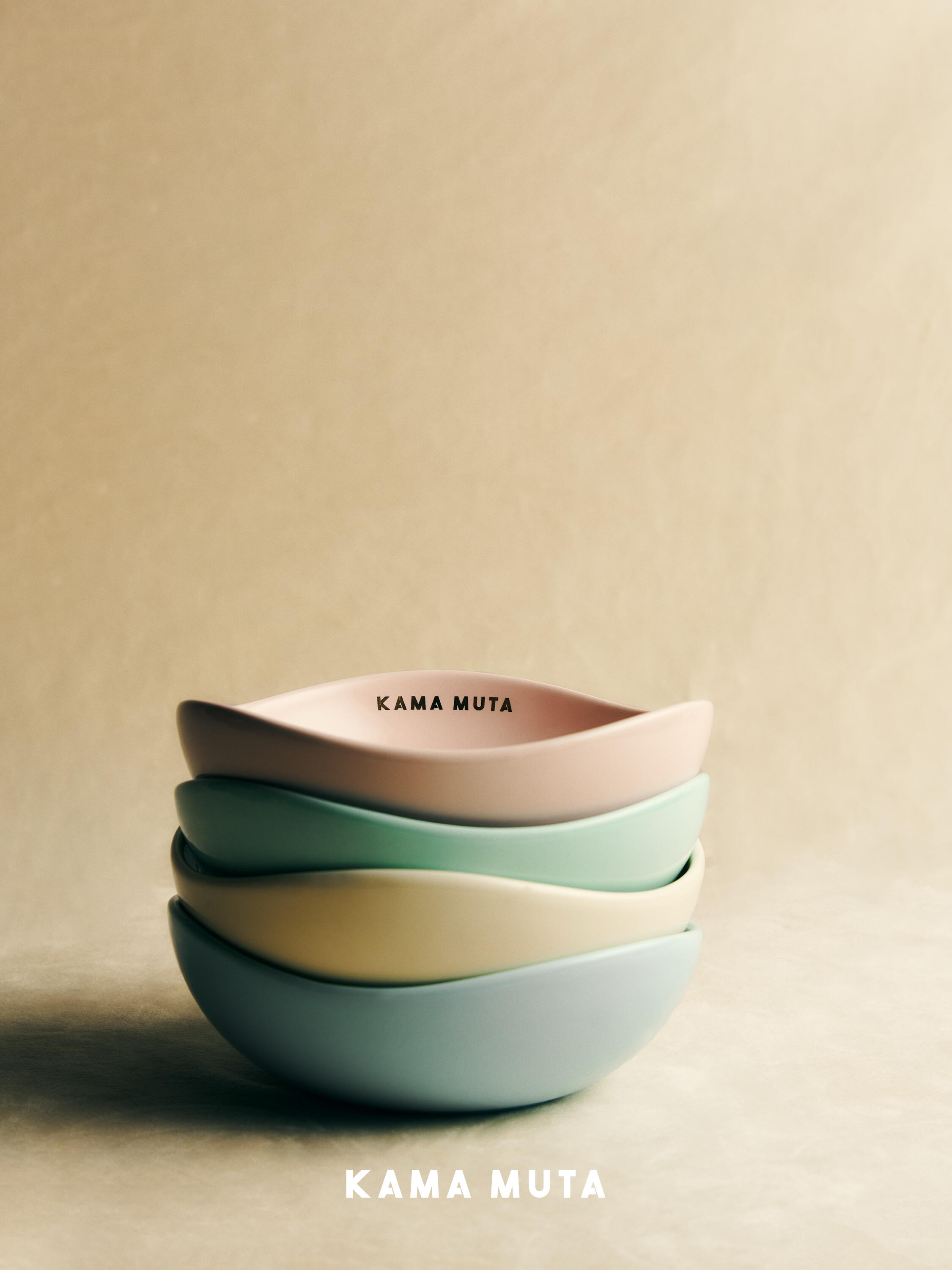 Minimalist ceramic pet bowls stacked in soft pastel colors, featuring a smooth bean-shaped design.