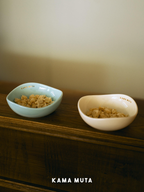 Two ceramic pet bowls holding dry food, placed on a wooden shelf to create a calm and minimalist feeding setup.