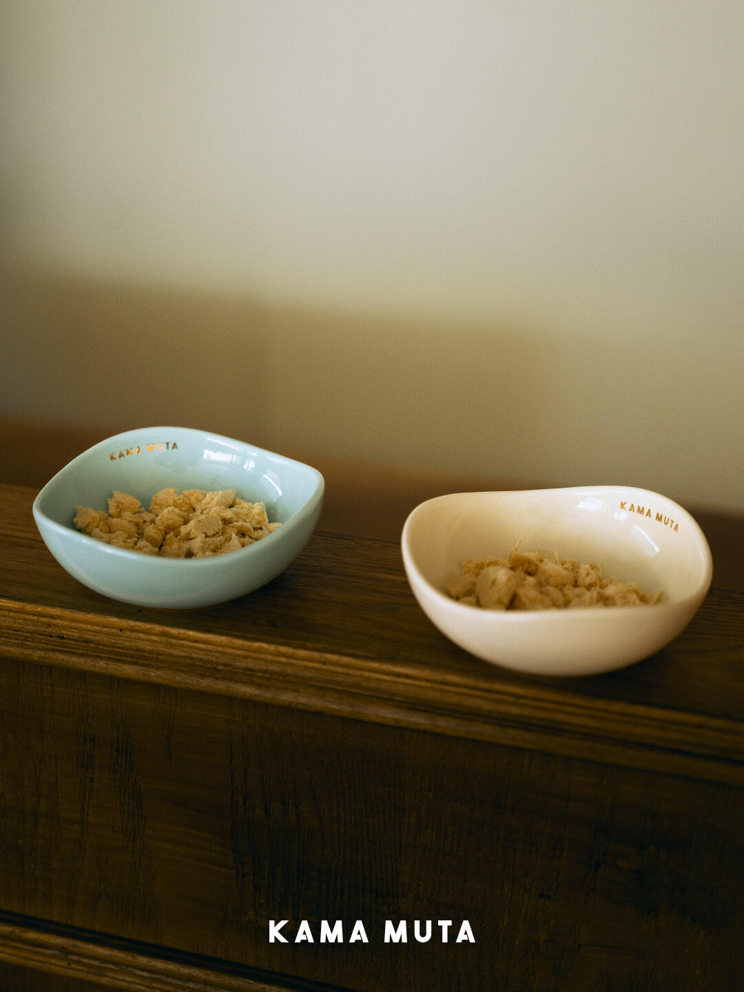 Two ceramic pet bowls holding dry food, placed on a wooden shelf to create a calm and minimalist feeding setup.