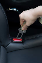 Hand inserting the dog car seatbelt tether into a standard car seat belt buckle, showing quick one-click attachment.