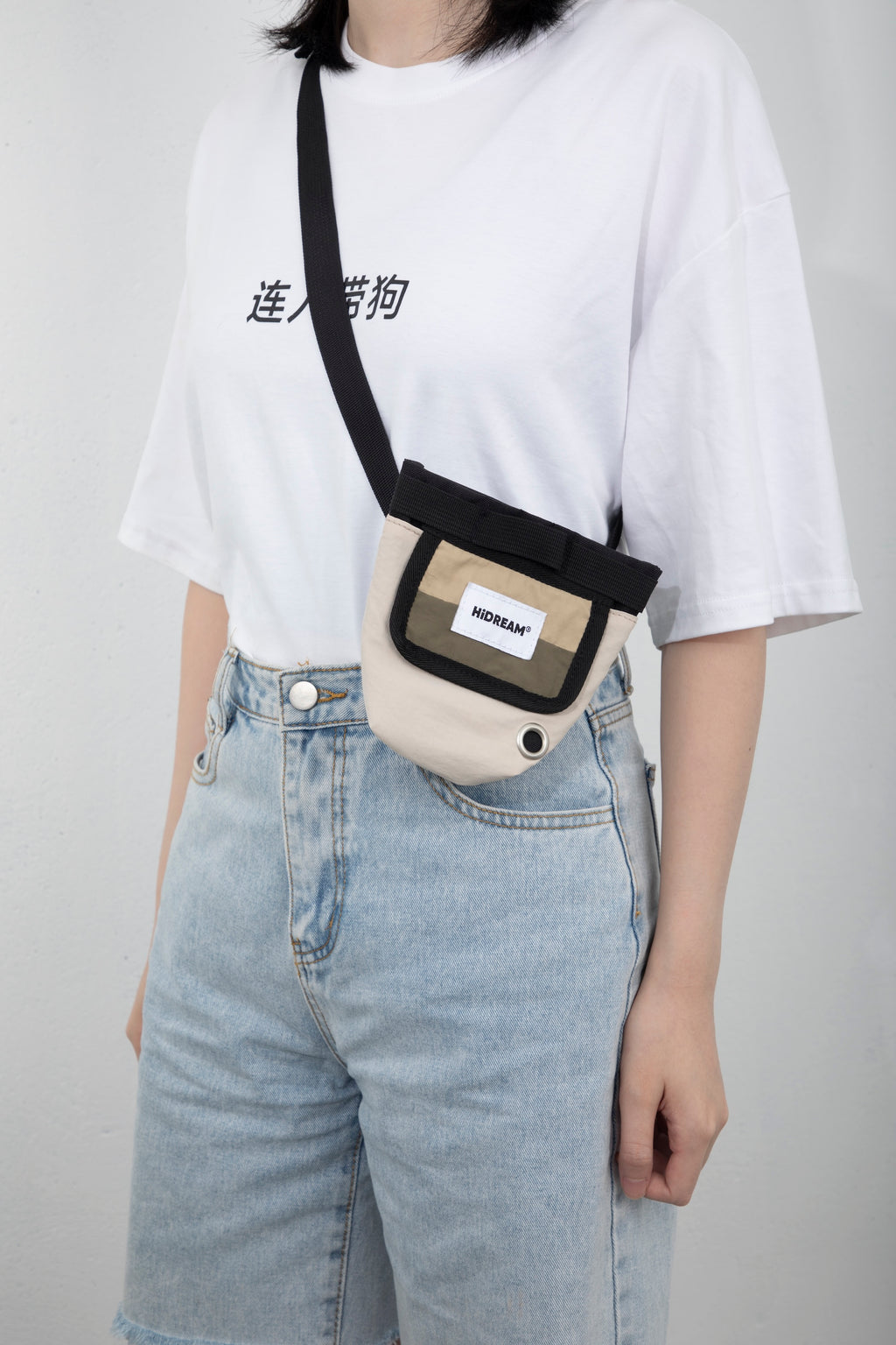 Dog treat pouch worn crossbody with an adjustable strap, showing the pouch size, front label panel, and hands-free carrying style.