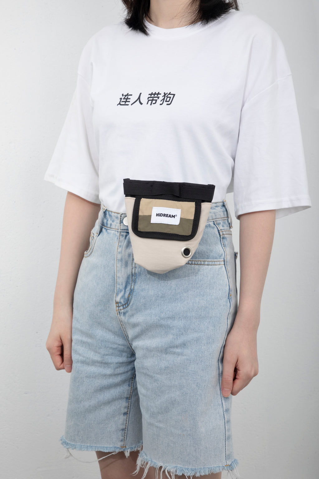 Front view of a dog treat pouch worn on a waist belt, showing the compact treat bag profile and the front pocket panel.