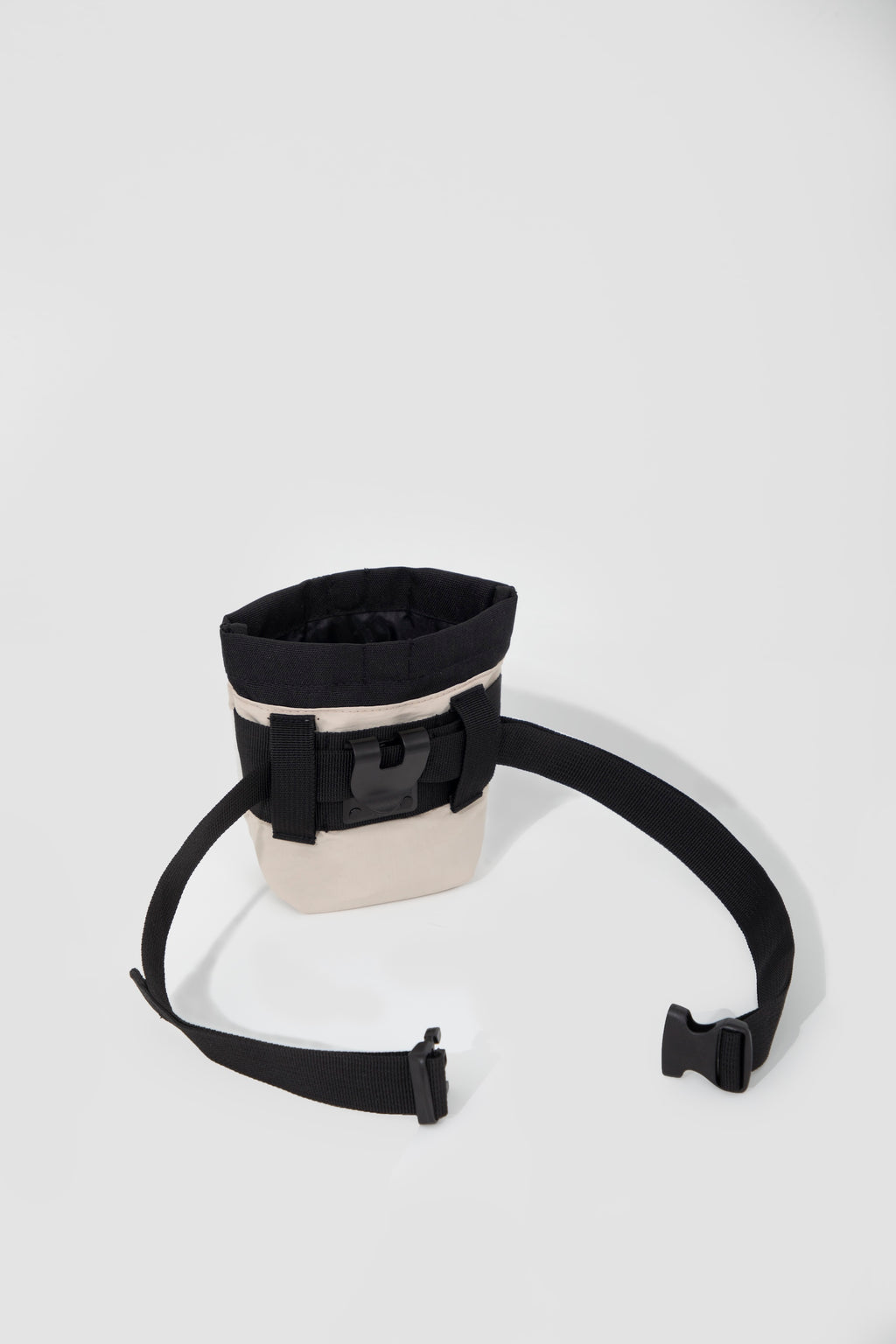 Flat lay of a dog treat pouch with the adjustable waist strap and buckle laid out, showing the back attachment area and hands-free belt setup.
