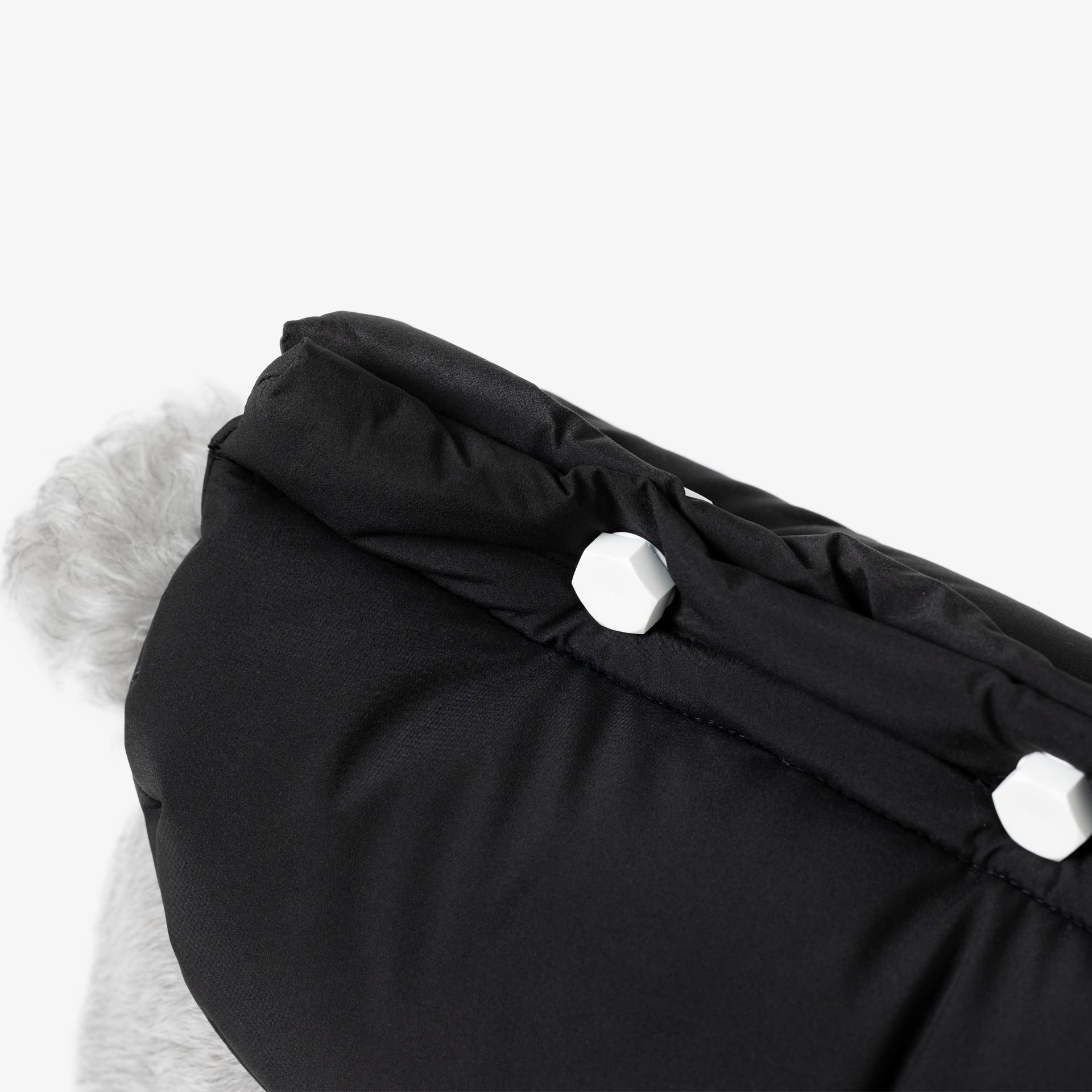 Close-up of removable decorative bolts on the back of a padded dog vest, combining functional fastening with minimalist design.