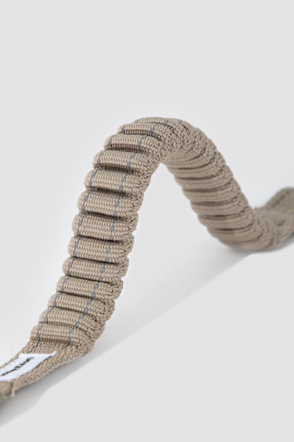 Close-up of elastic shock-absorbing webbing on a dog car seatbelt tether, designed to reduce sudden pulling force.