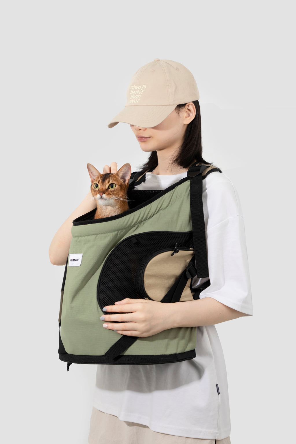 Model wearing a green front-facing cat carrier showing ergonomic fit, breathable mesh, and stable front carry design
