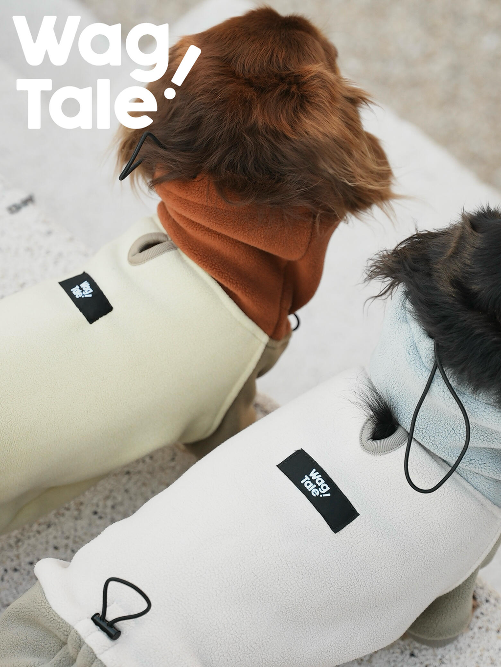 Close-up of two dogs wearing fleece dog suits, highlighting the soft textured fabric, back label placement, and adjustable loop details designed for a comfortable winter fit.