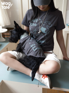 A person wearing a dark grey graphic cotton T-shirt sits with a dog in a matching dog jumper on their lap, showing coordinated print design for everyday wear.