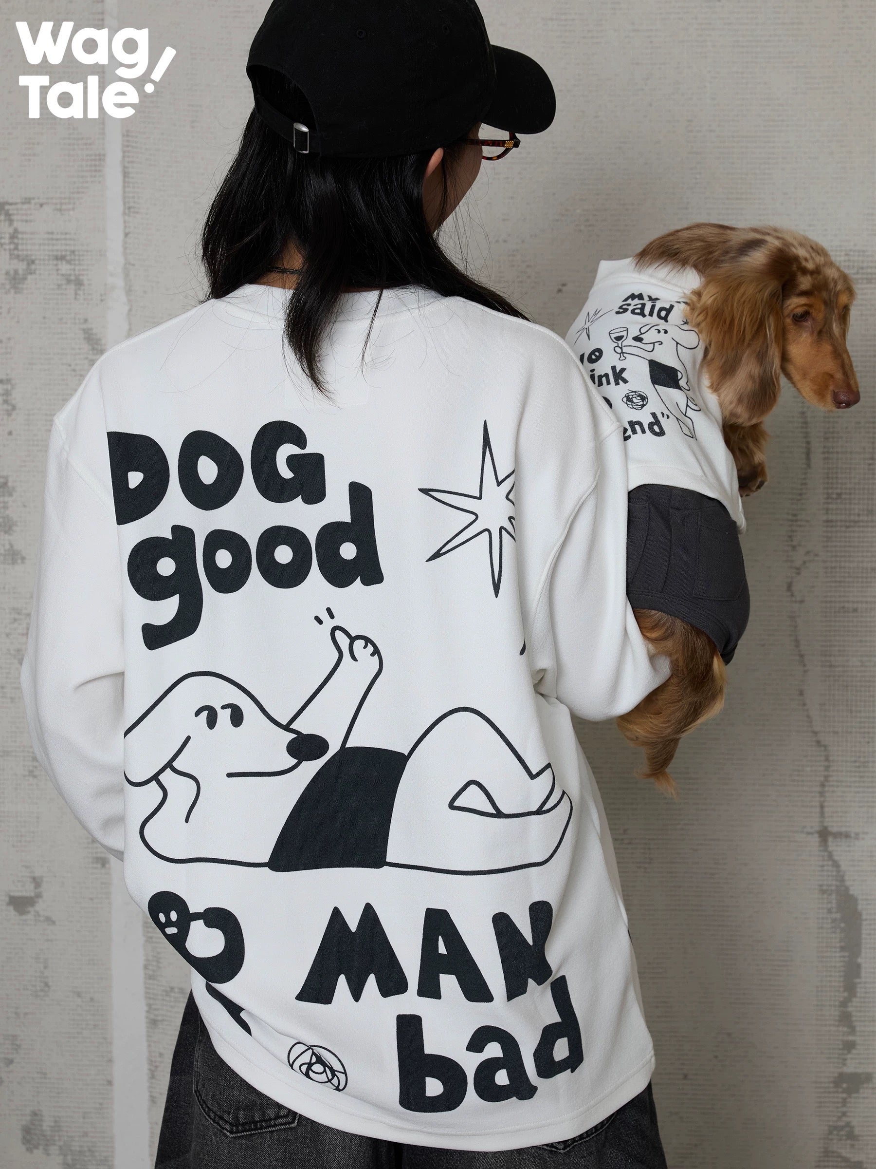 A person holding a dog dressed in a graphic dog jumper, highlighting matching prints across human top and dog jumper in a street-style look.