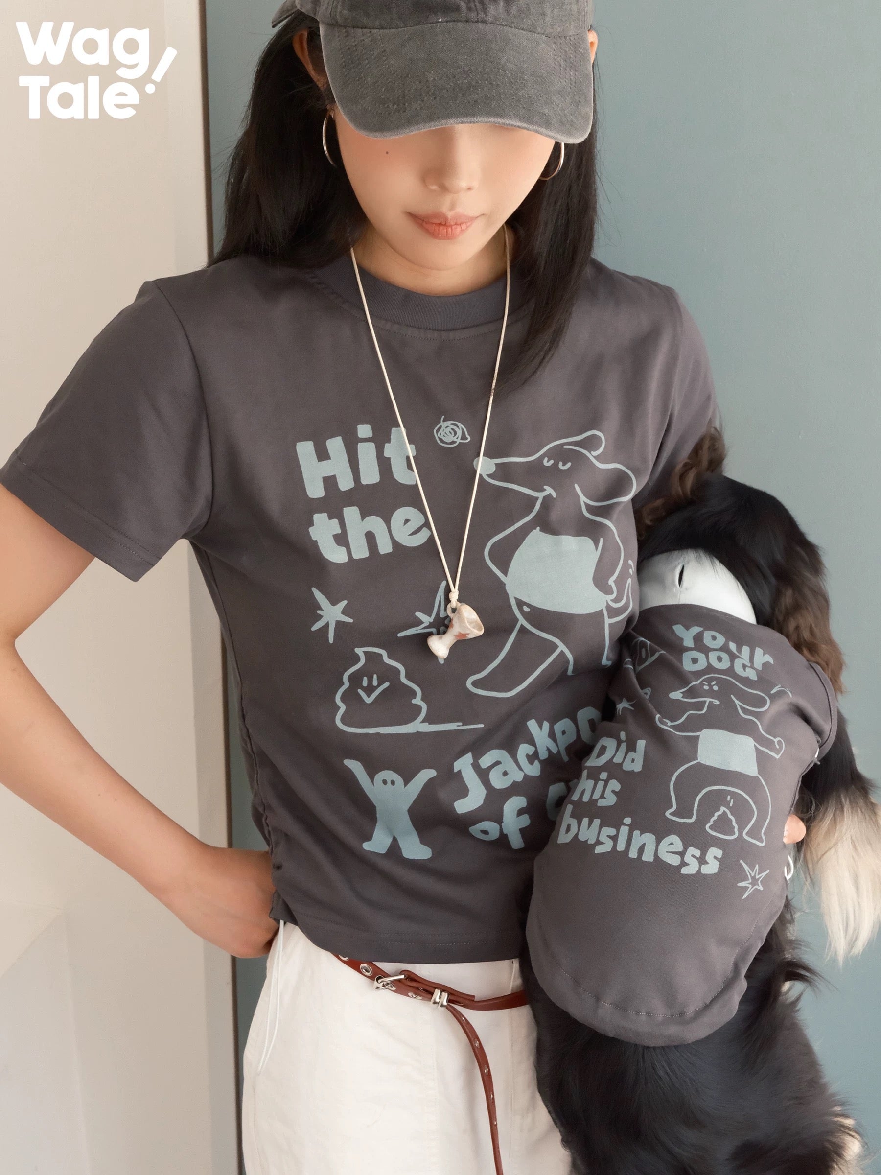 A person wearing a graphic T-shirt while holding a dog dressed in a matching graphic dog vest, highlighting coordinated print design.