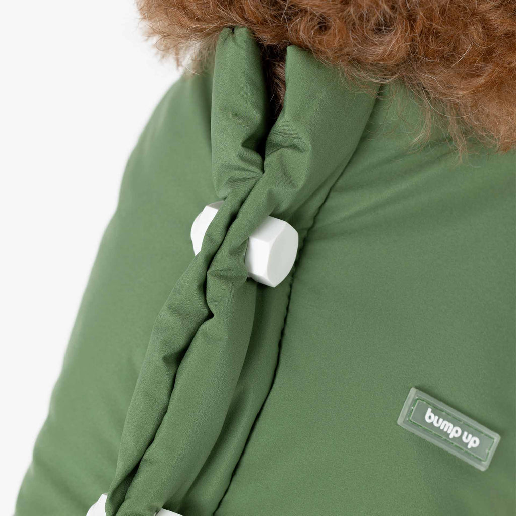 Close-up of the back detail on a green dog vest, featuring removable decorative bolts and a subtle brand label.