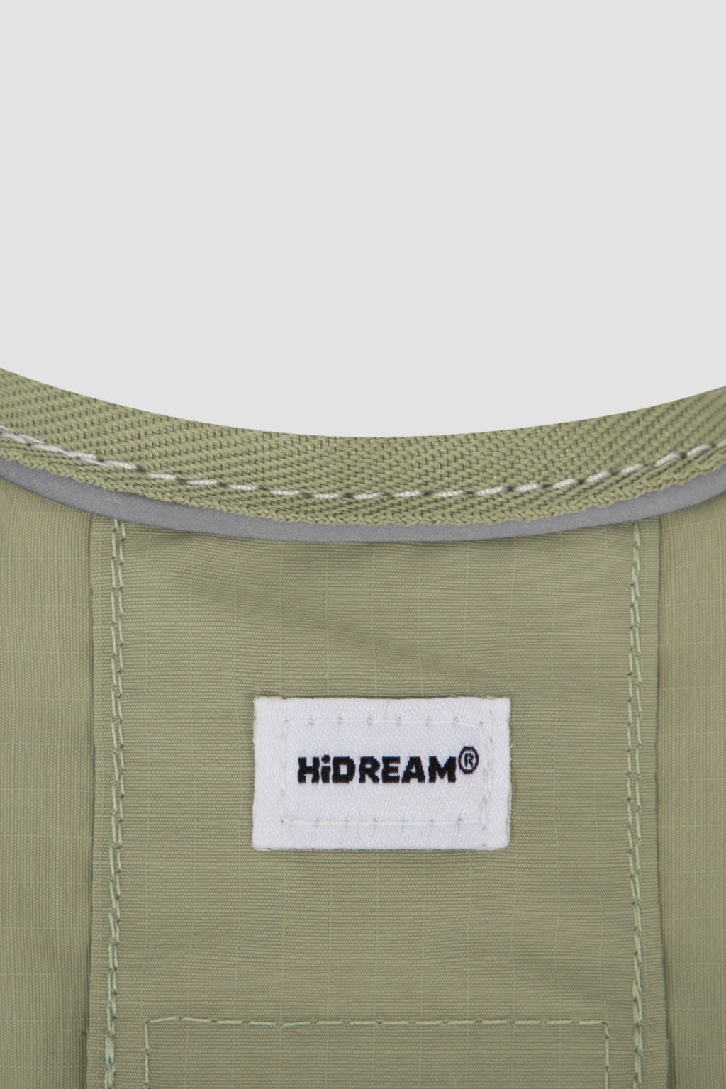 Close-up of the Hidream label stitched on a green cat harness, clearly showing the harness fabric texture and material detail.