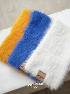 Hound-Co's collection of fuzzy knit snoods in mustard yellow, cobalt blue, and ivory, displayed together to showcase color options for sighthound owners.