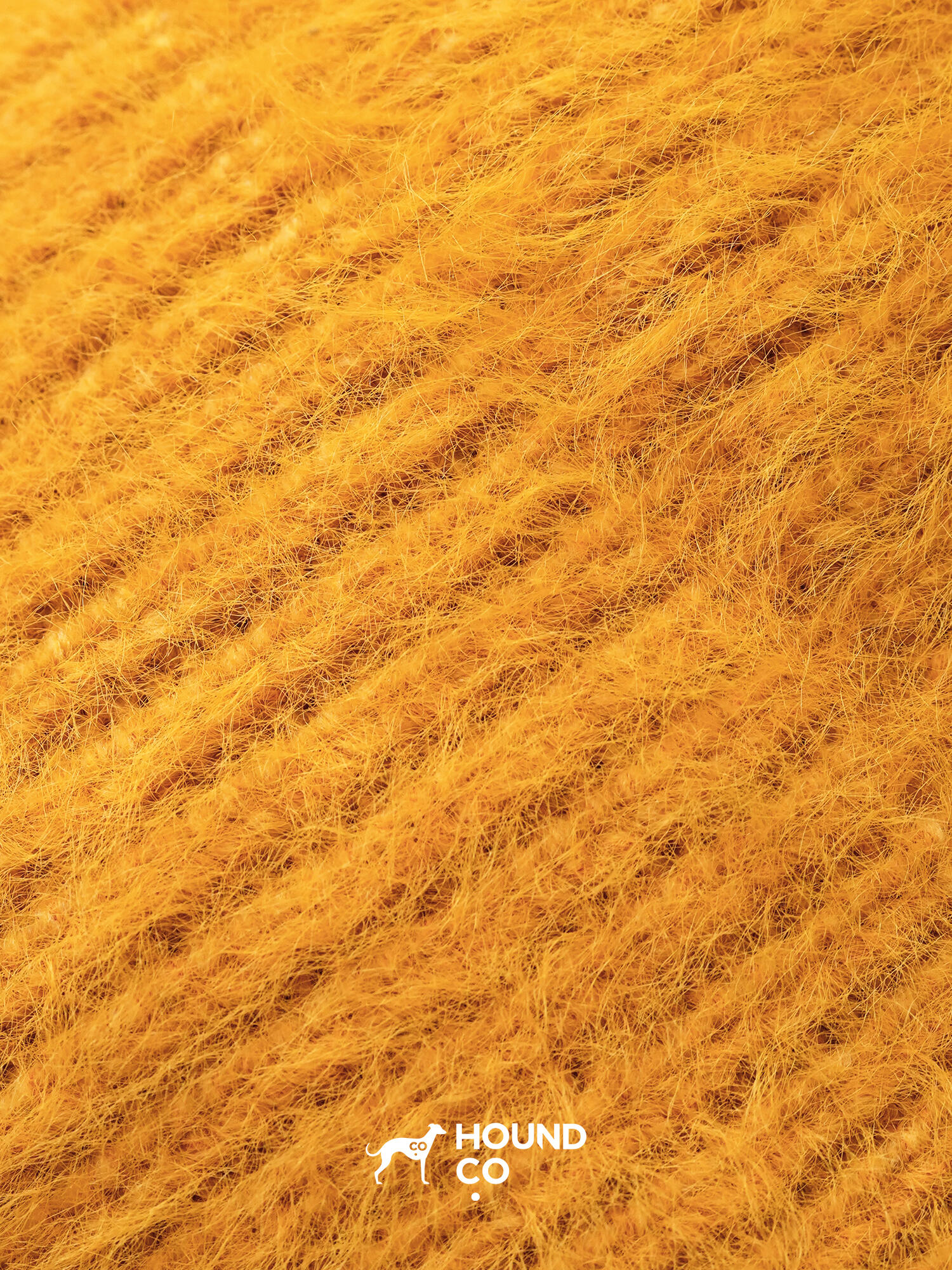 Close-up of Hound Co.'s mustard yellow fuzzy knit fabric, showcasing its soft, plush texture ideal for cozy winter dog accessories.