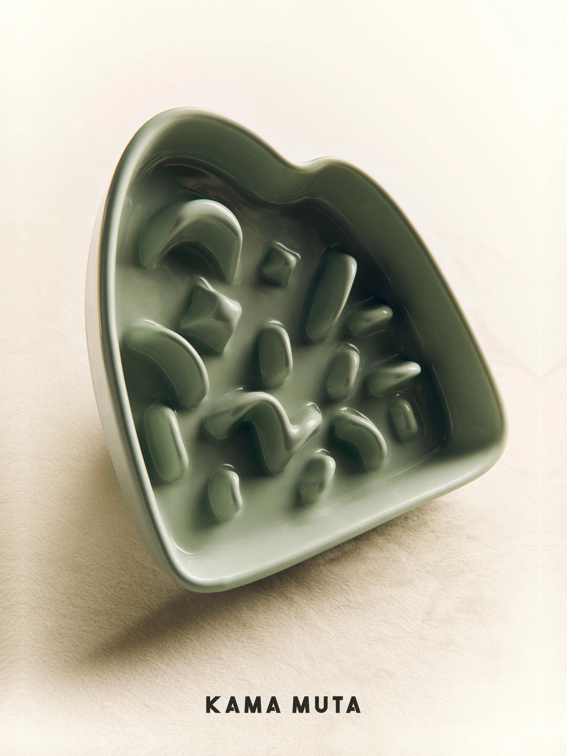 Light green heart-shaped ceramic slow feeder bowl for dogs (KAMA MUTA brand) with raised maze patterns