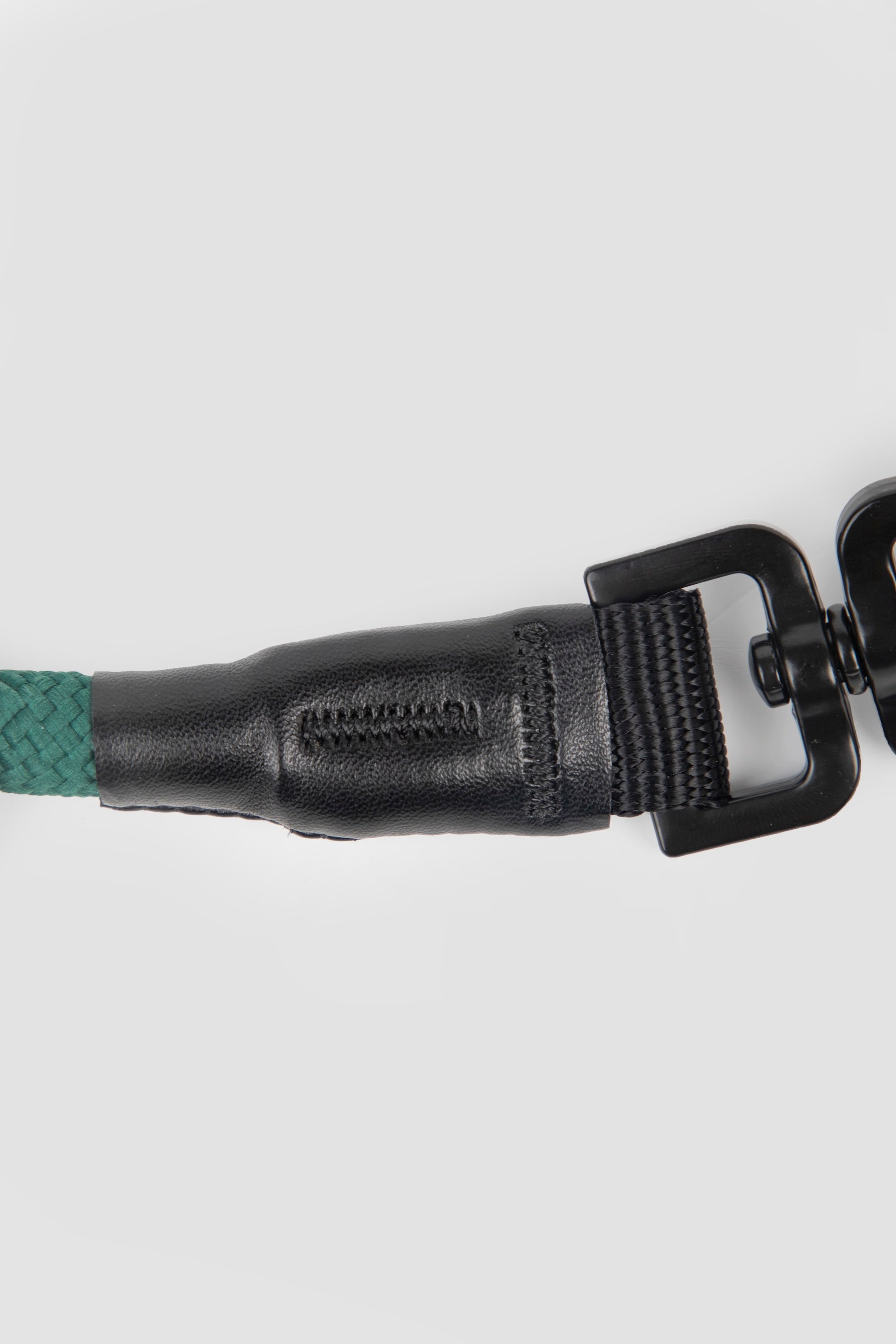 Close-up of leather-trimmed connector on a dog leash, highlighting stitched leather detail and hardware connection.