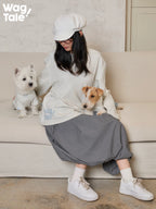 A person sitting on a sofa with two dogs wearing graphic dog jumpers, showing casual four-leg design and coordinated human and dog outfits