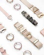 Flat lay of dog collar components showing metal buckle straps, adjustable webbing, and circular AirTag holders in different colors