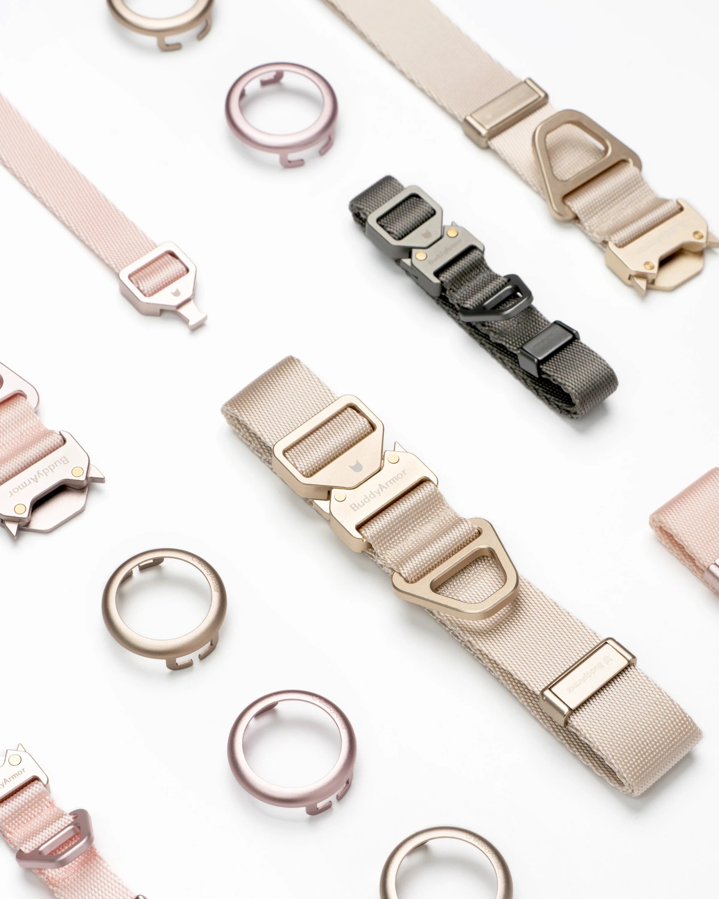 Flat lay of dog collar components showing metal buckle straps, adjustable webbing, and circular AirTag holders in different colors