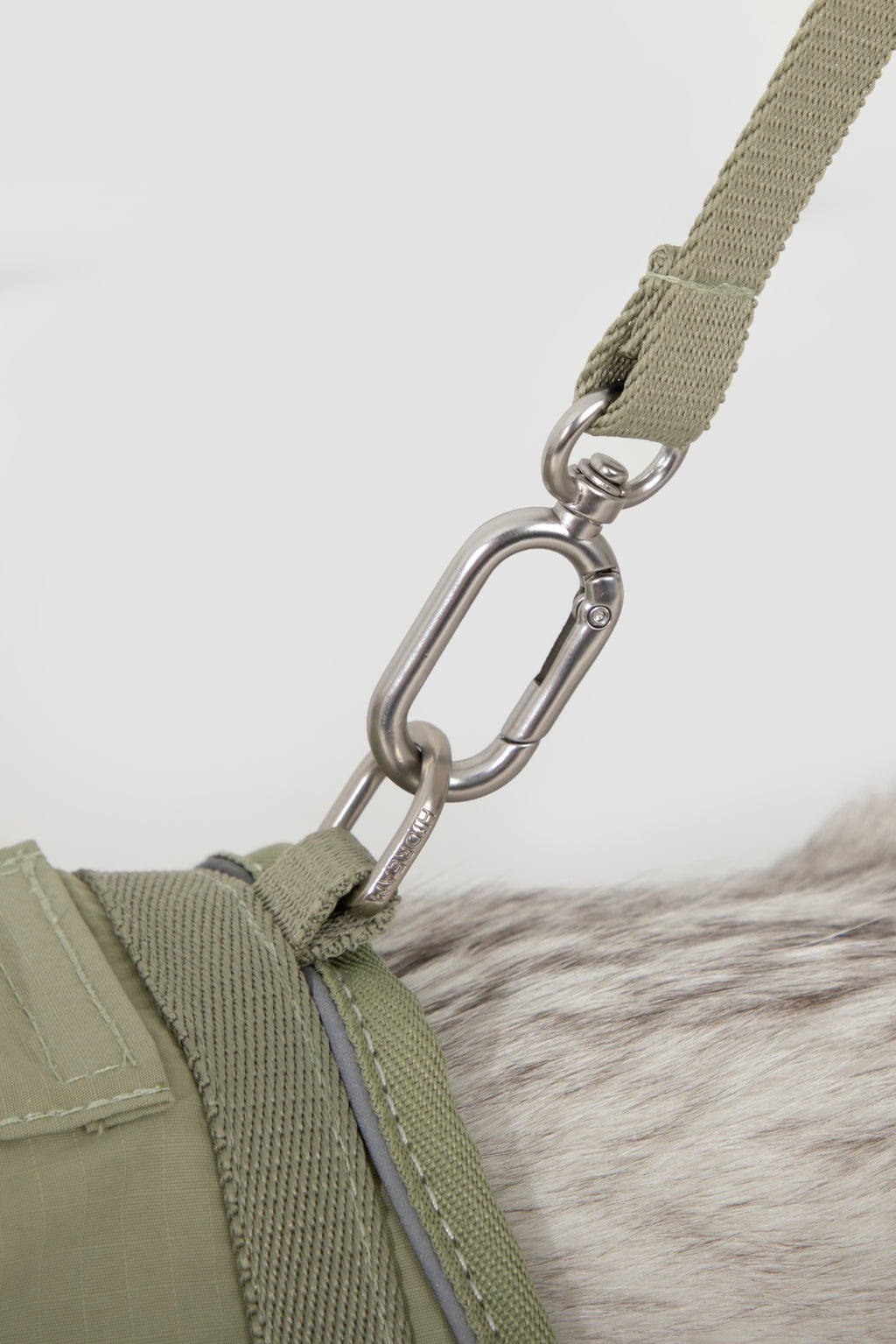 Close-up of metal leash clip attached to the cat harness D-ring, showing secure hardware connection for a cat collar harness set with leash.