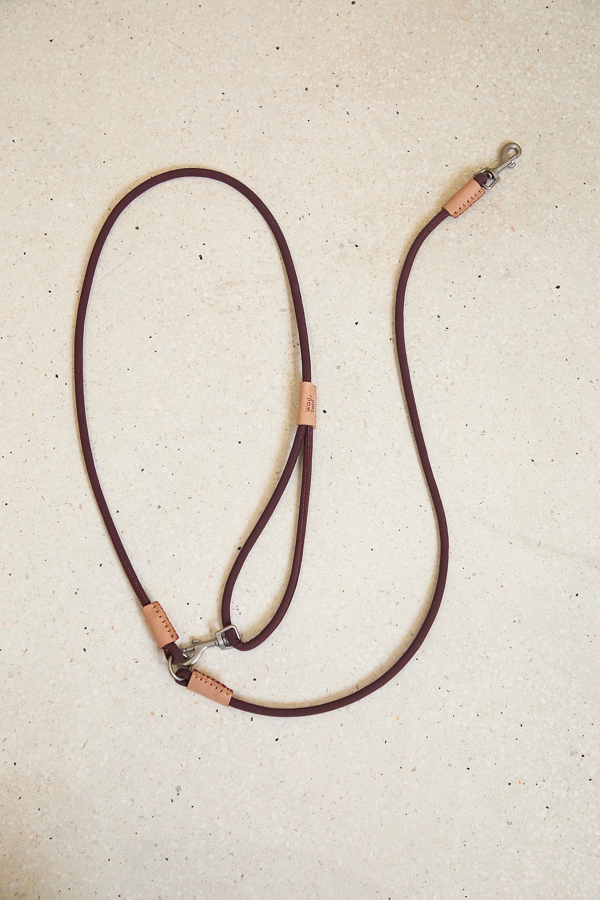 Multi-way dog leash in burgundy laid flat, featuring adjustable connection points, durable metal clips, and a vintage-inspired color tone.
