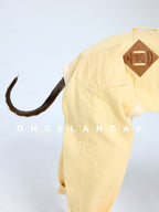 Close-up detail of ONCELANDAY yellow dog denim jeans showing the leather patch label, back pocket stitching, and woven denim texture with the tail opening visible