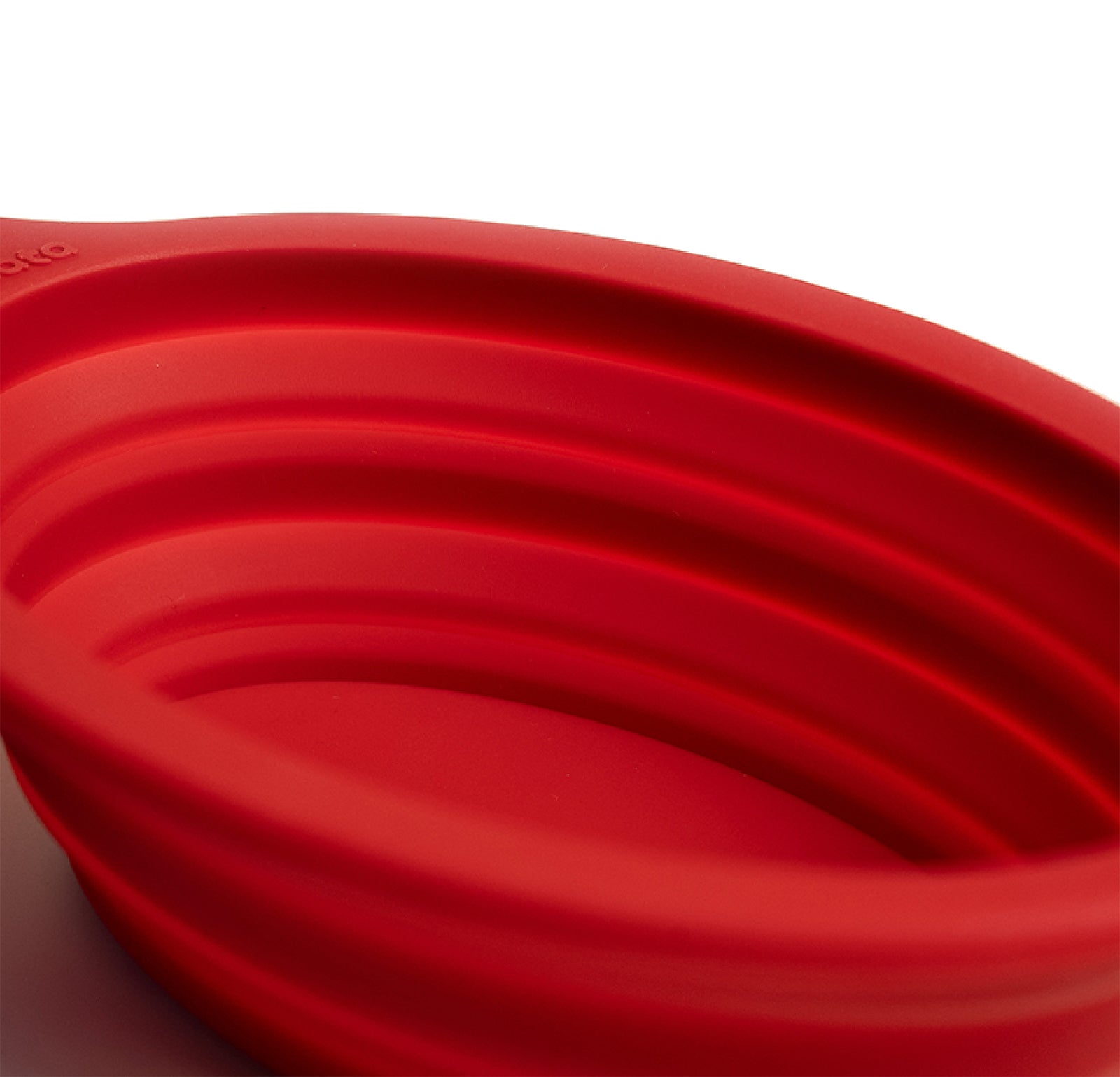 Close-up of a red silicone collapsible bowl on a white background