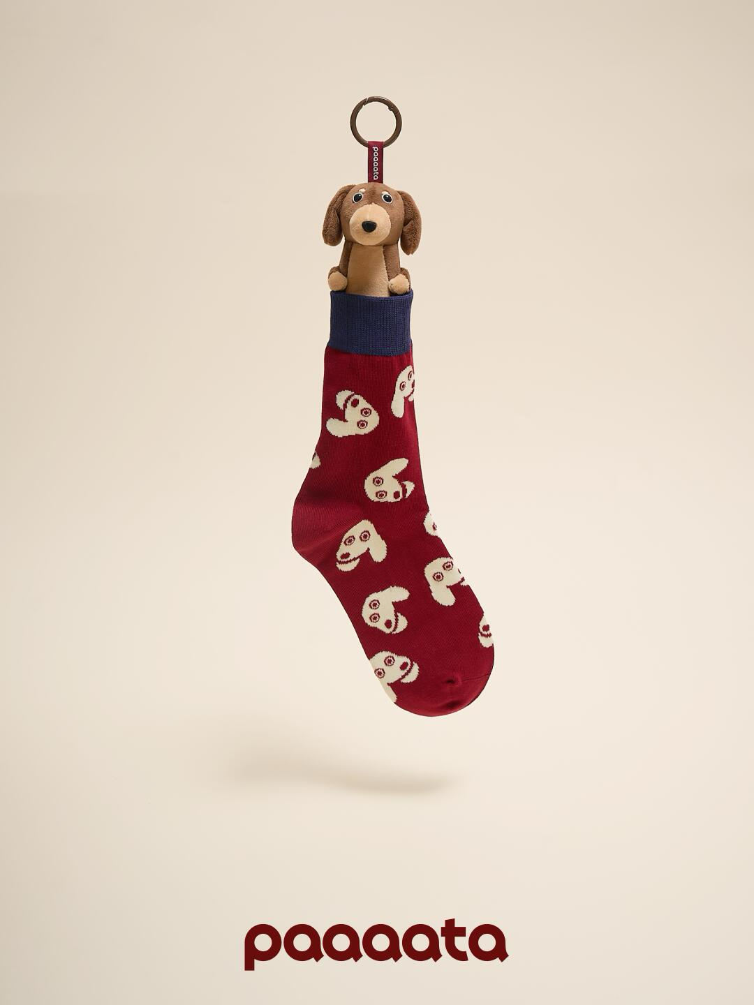 Red sock with dog pattern and keychain on beige background, featuring brand 'paaaata'.