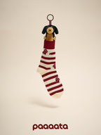 Striped sock with a small dog plush toy hanging from it on a beige background