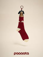 Red sock with a black and brown dog toy hanging from it on a beige background