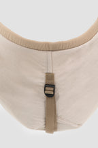 Close-up of the bottom of a pet sling carrier showing the external support strap and buckle that help maintain the bag’s shape and prevent collapse.