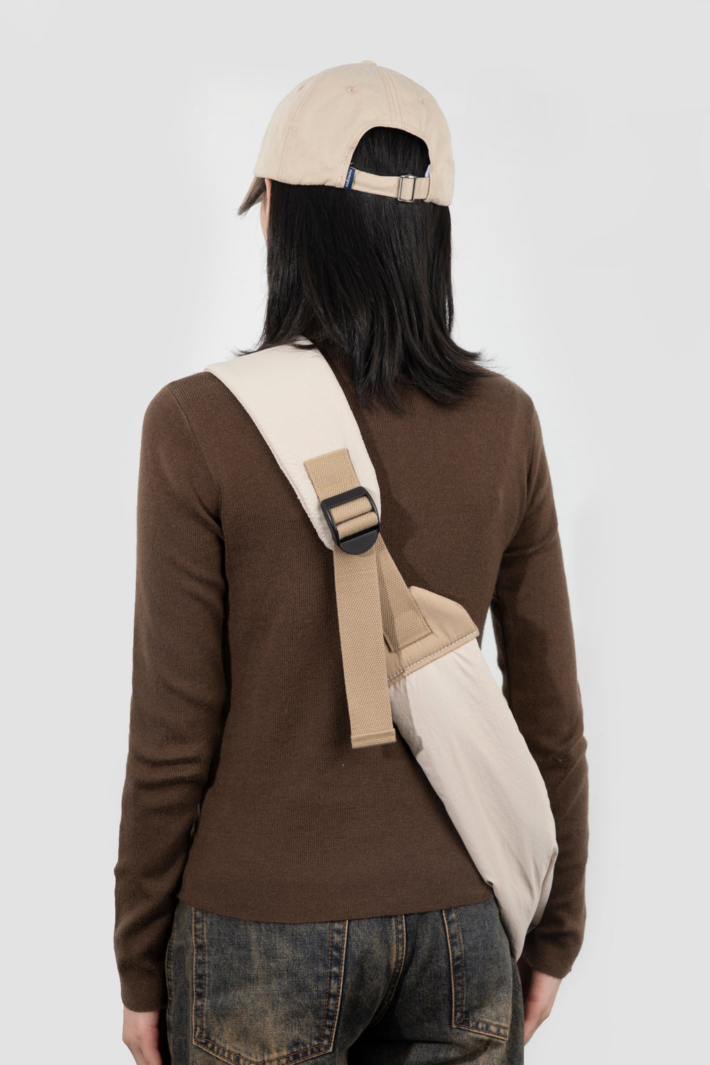 Back view of a pet sling carrier worn diagonally on the body, showing the wide shoulder strap, adjustable buckle, and how the sling sits securely against the back.