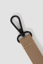 Close-up of a black metal hanging hook attached to the webbing strap of the pet sling carrier, showing the clasp and stitching details.
