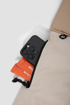 Close-up of the side zip pocket on the pet sling carrier with a smartphone and small items inside, showing the zipper opening and fabric texture.