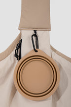 Detail of the shoulder strap area on a pet sling carrier, featuring a hanging hook with a collapsible pet bowl attached for daily outings.
