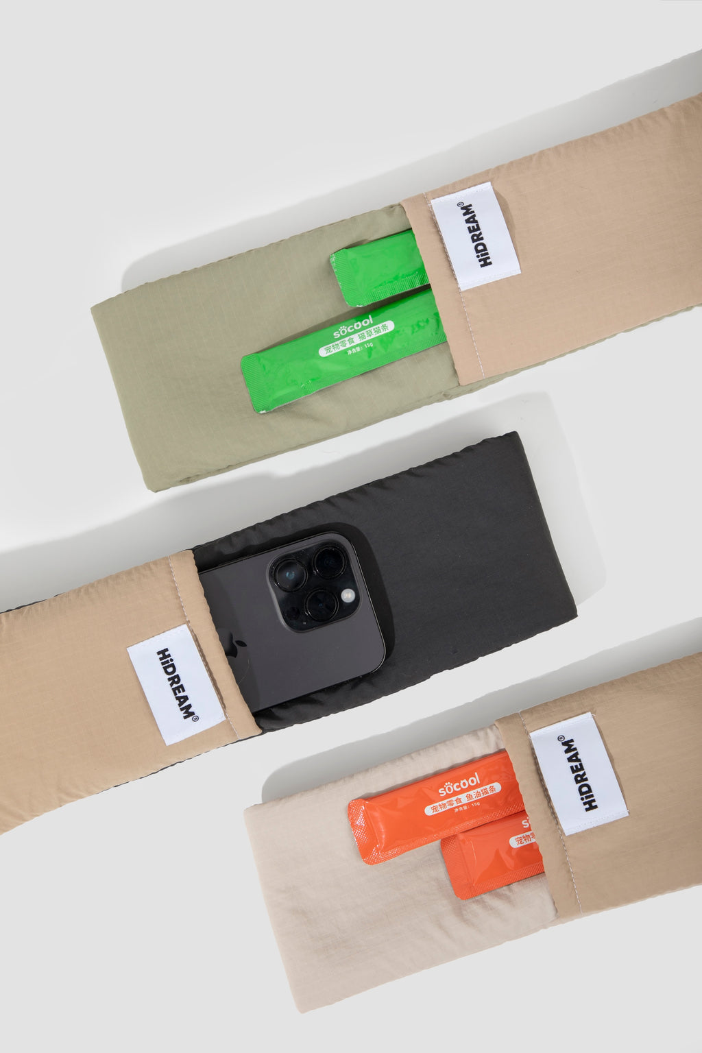 Top view of the shoulder strap pockets on the pet sling carrier, holding a smartphone and small snack packs, showing built-in storage along the strap.